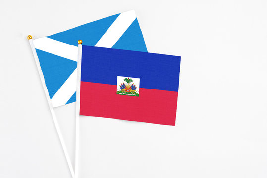 Haiti and Scotland stick flags on white background. High quality fabric, miniature national flag. Peaceful global concept.White floor for copy space.