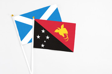 Papua New Guinea and Scotland stick flags on white background. High quality fabric, miniature national flag. Peaceful global concept.White floor for copy space.