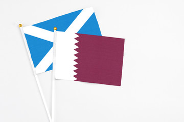 Qatar and Scotland stick flags on white background. High quality fabric, miniature national flag. Peaceful global concept.White floor for copy space.