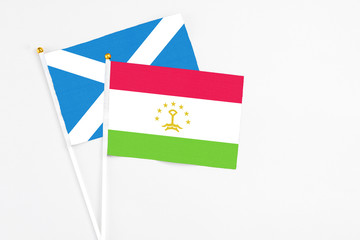 Tajikistan and Scotland stick flags on white background. High quality fabric, miniature national flag. Peaceful global concept.White floor for copy space.