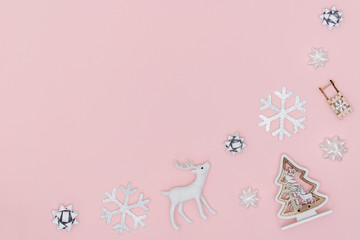 New Year and Christmas composition. Frame from snowflakes, chrismas tree, gift bows, deer on pastel pink paper background. Top view, flat lay, copy space