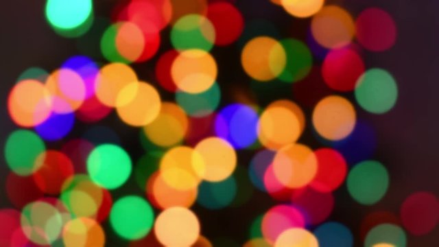 An out of focus Christmas theme background with multi-colored twinkle lights on a Christmas tree at night