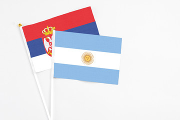 Argentina and Serbia stick flags on white background. High quality fabric, miniature national flag. Peaceful global concept.White floor for copy space.