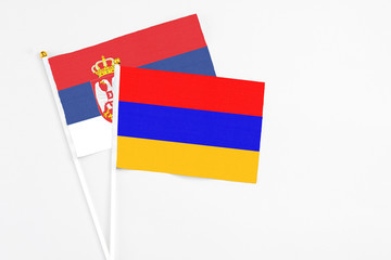 Armenia and Serbia stick flags on white background. High quality fabric, miniature national flag. Peaceful global concept.White floor for copy space.
