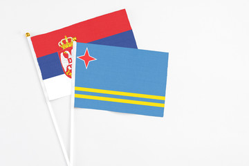 Aruba and Serbia stick flags on white background. High quality fabric, miniature national flag. Peaceful global concept.White floor for copy space.