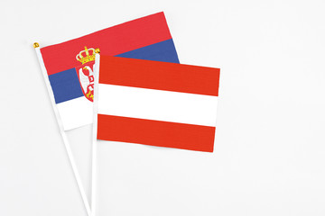 Austria and Serbia stick flags on white background. High quality fabric, miniature national flag. Peaceful global concept.White floor for copy space.