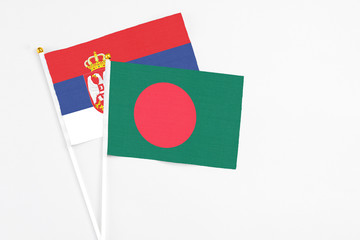 Bangladesh and Serbia stick flags on white background. High quality fabric, miniature national flag. Peaceful global concept.White floor for copy space.