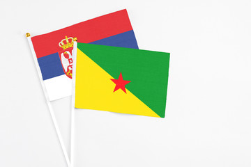 French Guiana and Serbia stick flags on white background. High quality fabric, miniature national flag. Peaceful global concept.White floor for copy space.
