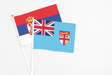 Fiji and Serbia stick flags on white background. High quality fabric, miniature national flag. Peaceful global concept.White floor for copy space.