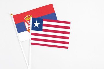 Liberia and Serbia stick flags on white background. High quality fabric, miniature national flag. Peaceful global concept.White floor for copy space.