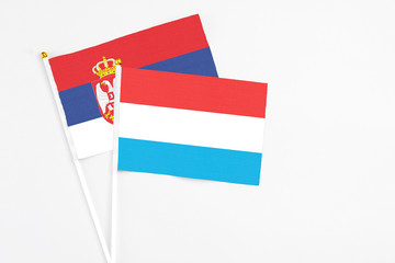 Luxembourg and Serbia stick flags on white background. High quality fabric, miniature national flag. Peaceful global concept.White floor for copy space.