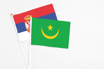 Mauritania and Serbia stick flags on white background. High quality fabric, miniature national flag. Peaceful global concept.White floor for copy space.