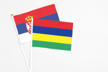 Mauritius and Serbia stick flags on white background. High quality fabric, miniature national flag. Peaceful global concept.White floor for copy space.