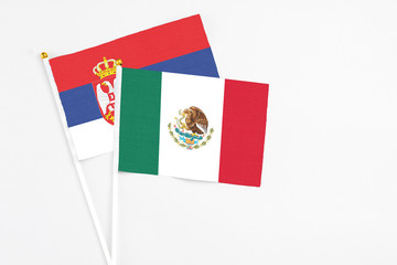 Mexico and Serbia stick flags on white background. High quality fabric, miniature national flag. Peaceful global concept.White floor for copy space.