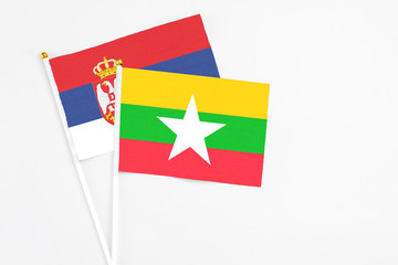 Myanmar and Serbia stick flags on white background. High quality fabric, miniature national flag. Peaceful global concept.White floor for copy space.