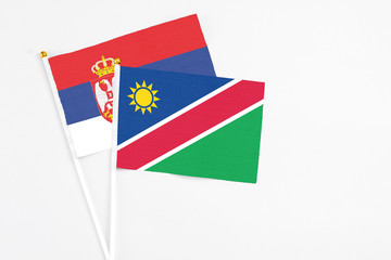 Namibia and Serbia stick flags on white background. High quality fabric, miniature national flag. Peaceful global concept.White floor for copy space.