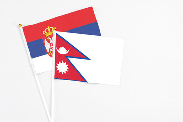 Nepal and Serbia stick flags on white background. High quality fabric, miniature national flag. Peaceful global concept.White floor for copy space.