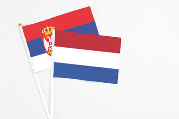 Netherlands and Serbia stick flags on white background. High quality fabric, miniature national flag. Peaceful global concept.White floor for copy space.