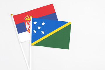 Solomon Islands and Serbia stick flags on white background. High quality fabric, miniature national flag. Peaceful global concept.White floor for copy space.