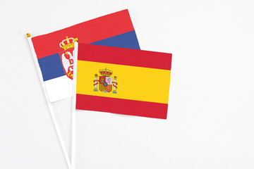 Spain and Serbia stick flags on white background. High quality fabric, miniature national flag. Peaceful global concept.White floor for copy space.