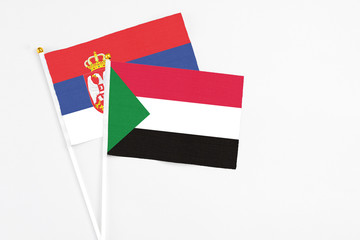 Sudan and Serbia stick flags on white background. High quality fabric, miniature national flag. Peaceful global concept.White floor for copy space.