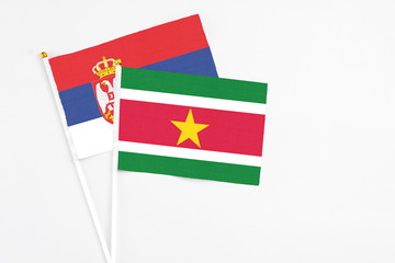 Suriname and Serbia stick flags on white background. High quality fabric, miniature national flag. Peaceful global concept.White floor for copy space.