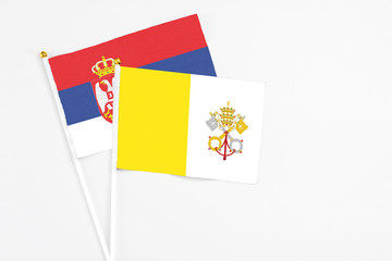 Vatican City and Serbia stick flags on white background. High quality fabric, miniature national flag. Peaceful global concept.White floor for copy space.