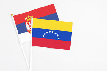 Venezuela and Serbia stick flags on white background. High quality fabric, miniature national flag. Peaceful global concept.White floor for copy space.