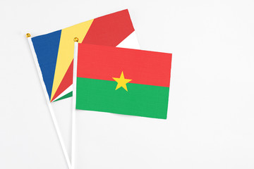 Burkina Faso and Seychelles stick flags on white background. High quality fabric, miniature national flag. Peaceful global concept.White floor for copy space.v