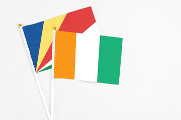 Cote D'Ivoire and Seychelles stick flags on white background. High quality fabric, miniature national flag. Peaceful global concept.White floor for copy space.v