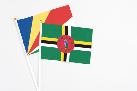 Dominica and Seychelles stick flags on white background. High quality fabric, miniature national flag. Peaceful global concept.White floor for copy space.v