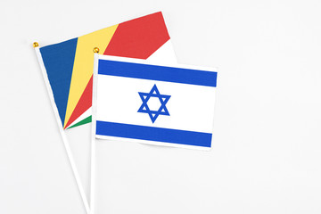 Fototapeta premium Israel and Seychelles stick flags on white background. High quality fabric, miniature national flag. Peaceful global concept.White floor for copy space.v