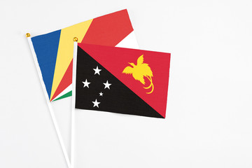 Papua New Guinea and Seychelles stick flags on white background. High quality fabric, miniature national flag. Peaceful global concept.White floor for copy space.v