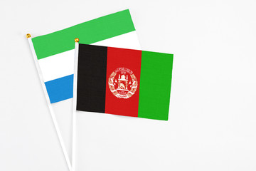 Afghanistan and Sierra Leone stick flags on white background. High quality fabric, miniature national flag. Peaceful global concept.White floor for copy space.