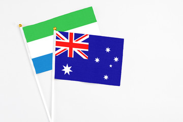 Fototapeta premium Australia and Sierra Leone stick flags on white background. High quality fabric, miniature national flag. Peaceful global concept.White floor for copy space.