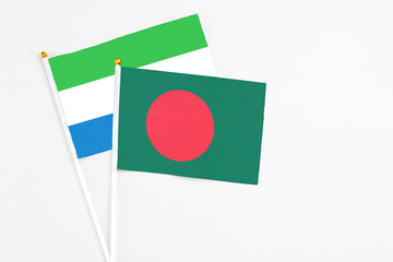 Bangladesh and Sierra Leone stick flags on white background. High quality fabric, miniature national flag. Peaceful global concept.White floor for copy space.