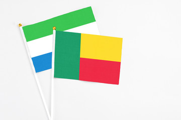 Benin and Sierra Leone stick flags on white background. High quality fabric, miniature national flag. Peaceful global concept.White floor for copy space.