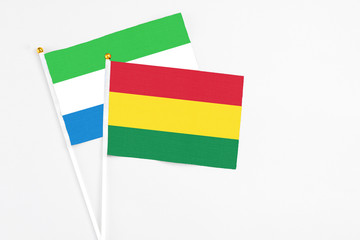 Bolivia and Sierra Leone stick flags on white background. High quality fabric, miniature national flag. Peaceful global concept.White floor for copy space.