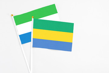 Gabon and Sierra Leone stick flags on white background. High quality fabric, miniature national flag. Peaceful global concept.White floor for copy space.