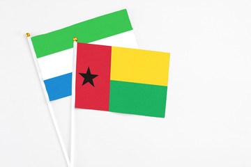 Guinea Bissau and Sierra Leone stick flags on white background. High quality fabric, miniature national flag. Peaceful global concept.White floor for copy space.