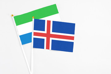 Obraz premium Iceland and Sierra Leone stick flags on white background. High quality fabric, miniature national flag. Peaceful global concept.White floor for copy space.