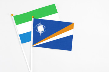 Marshall Islands and Sierra Leone stick flags on white background. High quality fabric, miniature national flag. Peaceful global concept.White floor for copy space.