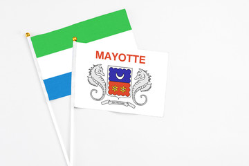 Mayotte and Sierra Leone stick flags on white background. High quality fabric, miniature national flag. Peaceful global concept.White floor for copy space.