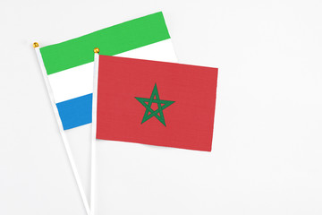 Morocco and Sierra Leone stick flags on white background. High quality fabric, miniature national flag. Peaceful global concept.White floor for copy space.