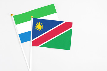 Namibia and Sierra Leone stick flags on white background. High quality fabric, miniature national flag. Peaceful global concept.White floor for copy space.