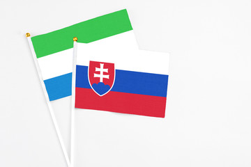 Slovakia and Sierra Leone stick flags on white background. High quality fabric, miniature national flag. Peaceful global concept.White floor for copy space.