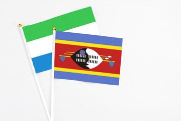 Swaziland and Sierra Leone stick flags on white background. High quality fabric, miniature national flag. Peaceful global concept.White floor for copy space.