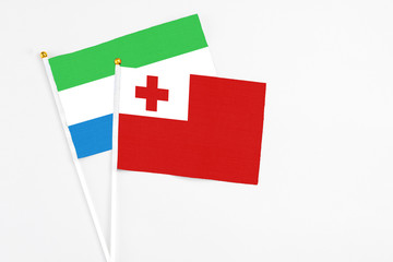 Tonga and Sierra Leone stick flags on white background. High quality fabric, miniature national flag. Peaceful global concept.White floor for copy space.