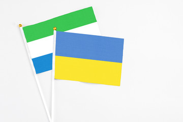 Ukraine and Sierra Leone stick flags on white background. High quality fabric, miniature national flag. Peaceful global concept.White floor for copy space.