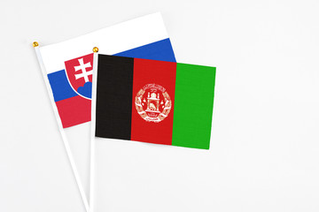 Afghanistan and Slovakia stick flags on white background. High quality fabric, miniature national flag. Peaceful global concept.White floor for copy space.